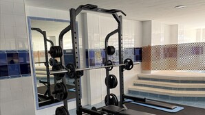 A gym with weightlifting equipment, a mirror, and a pool area. - Valparaiso Apartment Burriana Beach (Nerja)