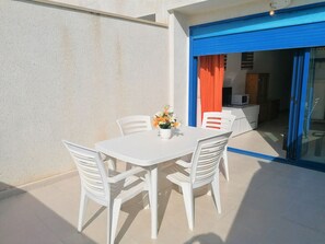 A white table with four chairs and a vase of flowers on a tiled patio. - Miralcielo Atico - LEK (Peñiscola)