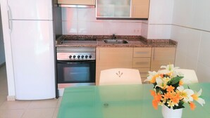 Une cuisine compacte équipée d’un réfrigérateur, d’une cuisinière, d’un four à micro-ondes et d’un évier.