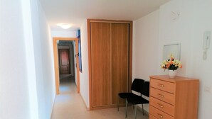 Un couloir avec une armoire en bois, un bureau avec une chaise et un miroir fixé au mur.