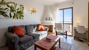 Un salon comprenant un canapé, une table basse, une cheminée, un fauteuil et une vue sur l’océan.