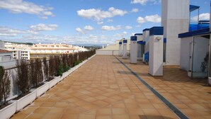 A rooftop terrace with tiled flooring, white columns, and a view of the cityscape. - Miralcielo 2ºA- LEK (Peñiscola)