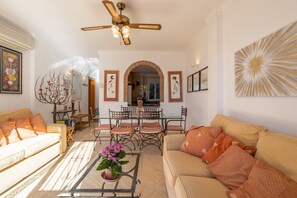 Uma sala de estar com sofá, mesa de centro e um espaço de refeições com cadeiras e mesa.