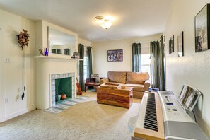 Un salon avec une cheminée, un canapé, un piano et un grand miroir.