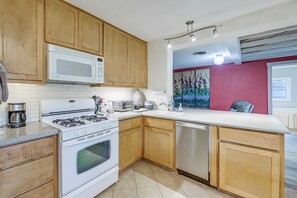 A kitchen with wooden cabinets, a microwave, a stove, a dishwasher, and a coffee maker. - Walk to Mueller Lake Park! Home w/ Patio & Yard (Austin)