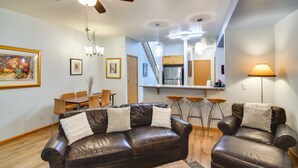 A living room with a brown leather sofa, a dining table, and a kitchen in the background. - Cozy Vail Valley Townhome - Walk to Riverwalk! (Edwards)