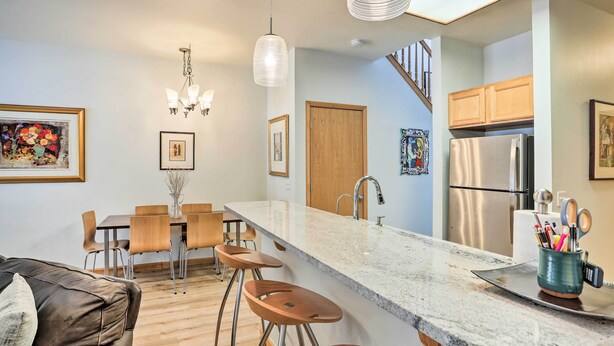 A modern kitchen with a marble countertop, wooden chairs, and a stainless steel refrigerator. - Cozy Vail Valley Townhome - Walk to Riverwalk! (Edwards)