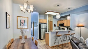 A modern kitchen with wooden cabinets, a stainless steel refrigerator, and a bar area with stools. - Cozy Vail Valley Townhome - Walk to Riverwalk! (Edwards)