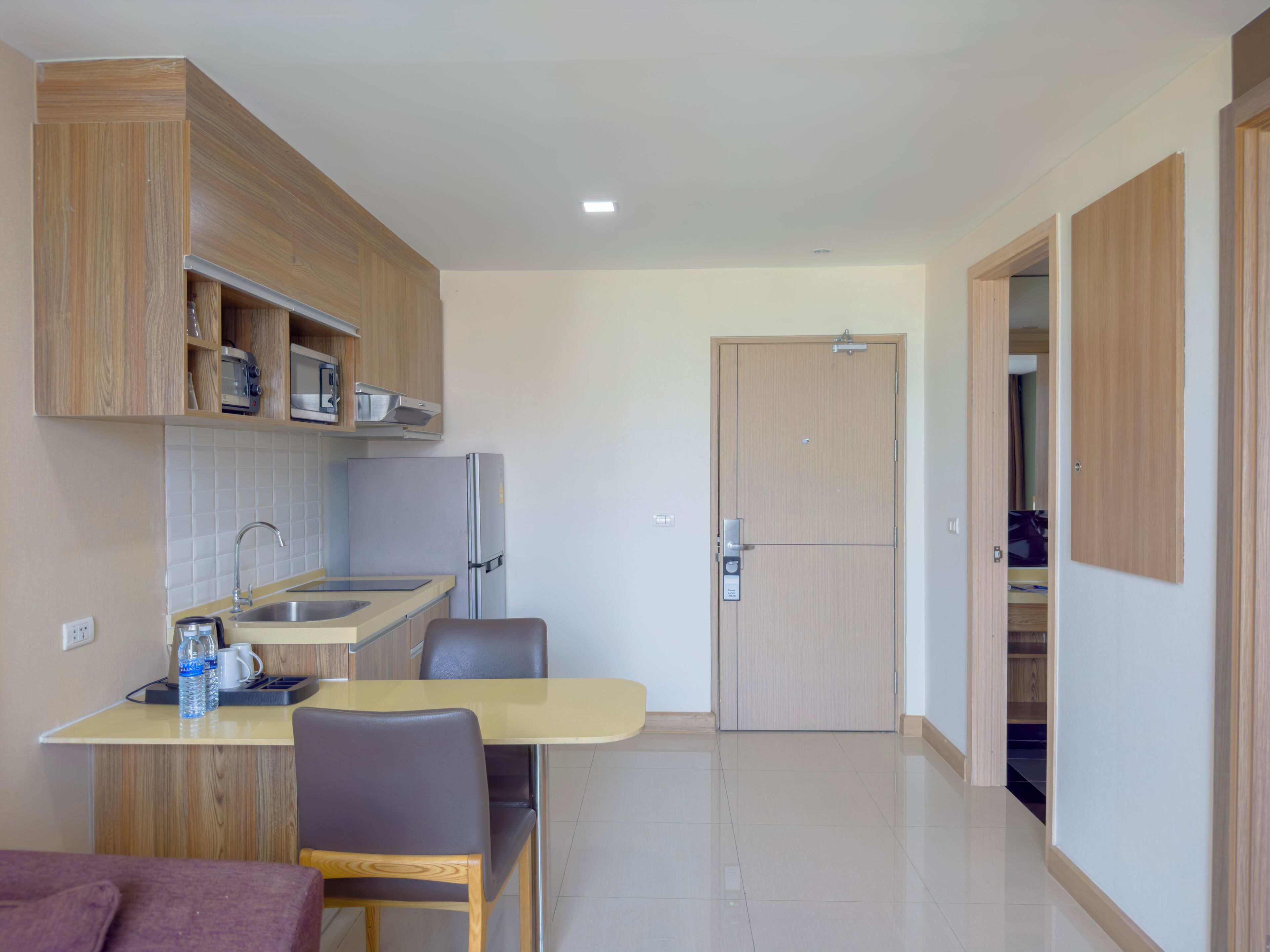 A compact kitchen with a dining area, a refrigerator, and wooden cabinets.