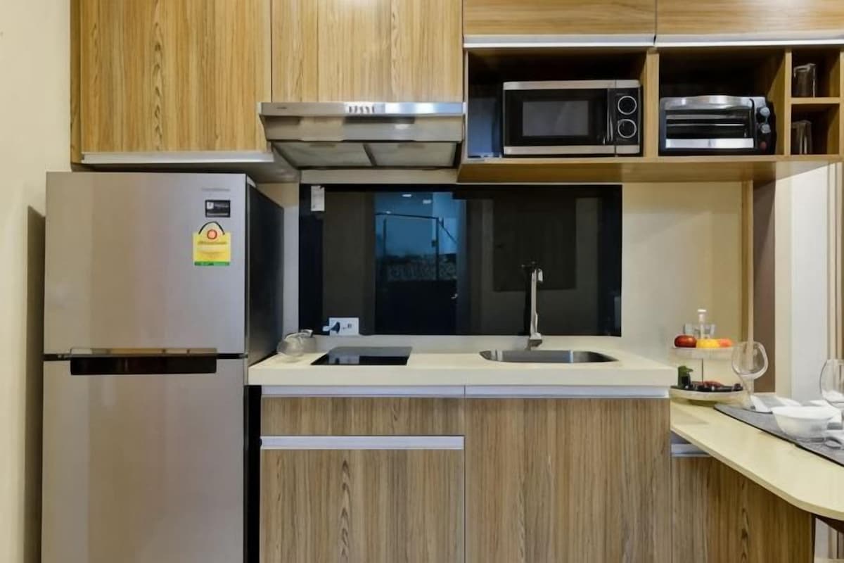 A kitchen with a stainless steel refrigerator, a microwave, a toaster, and wooden cabinets.