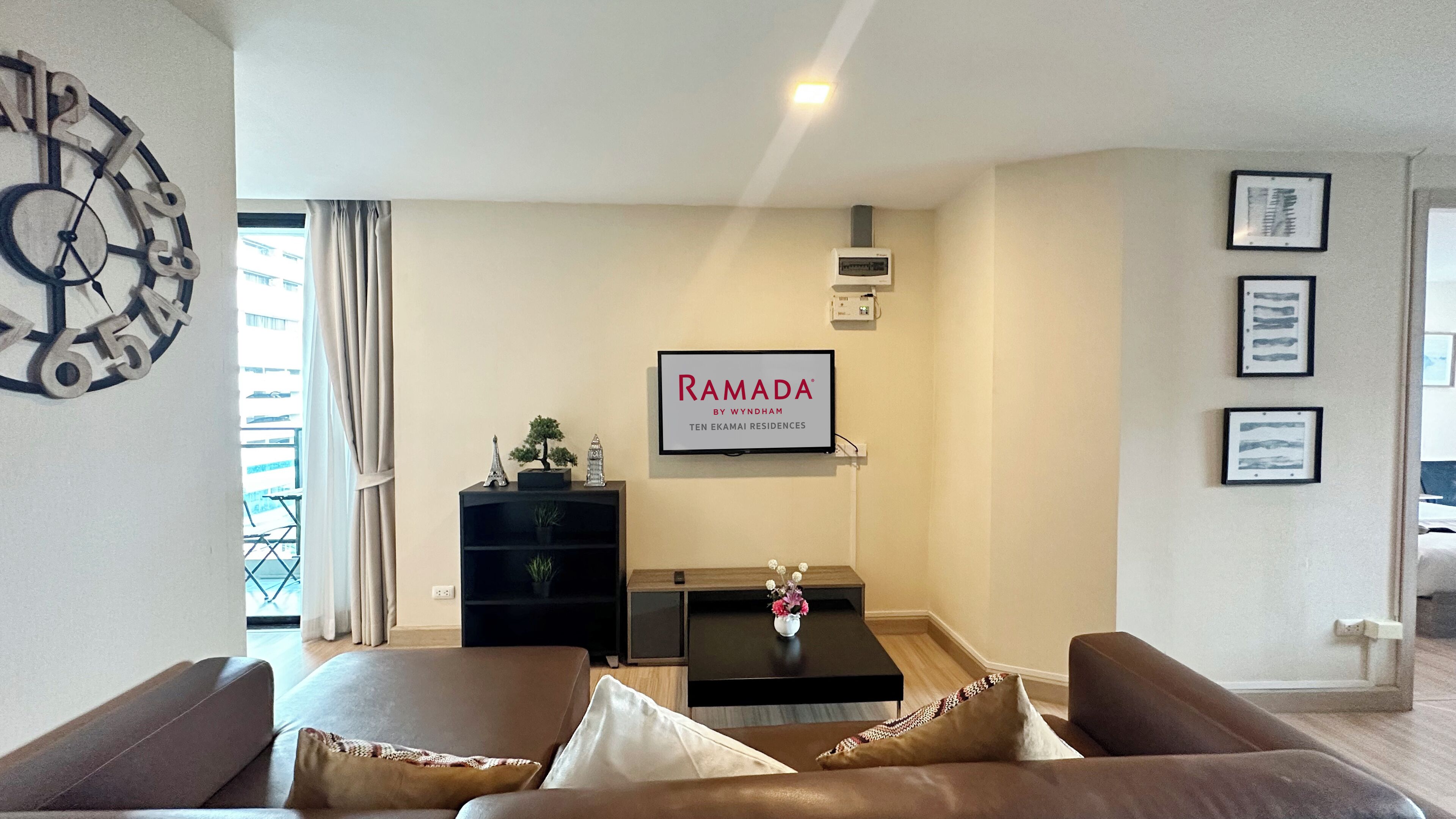 A modern living room with a sofa, a coffee table, a TV, and a clock on the wall.