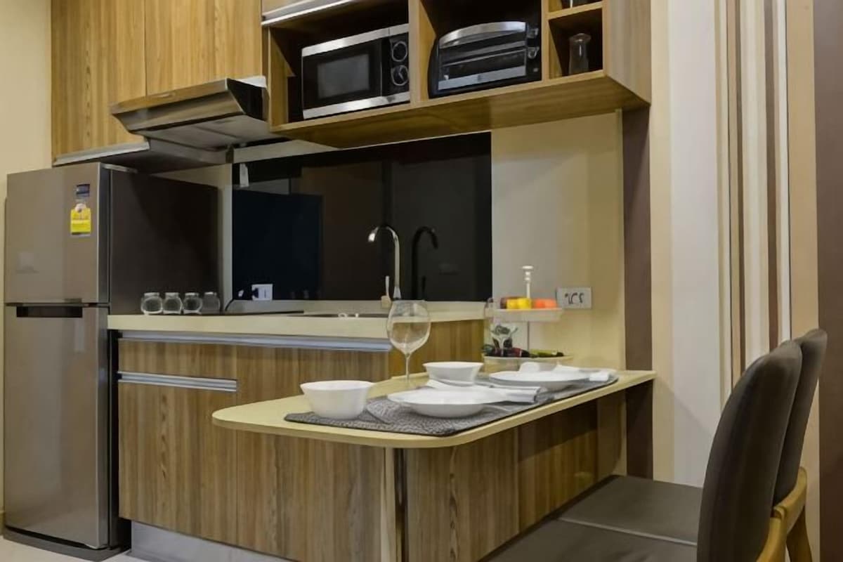 A compact kitchen with a microwave, oven, and sink. There is a small dining area with a table set for two.