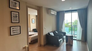 Een hotelkamer met een bed, een slaapbank, een tafeltje en een balkon met gordijnen.