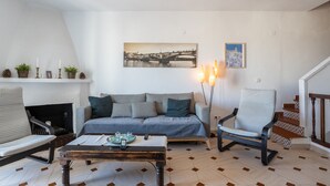 Uma sala de estar com sofá, poltronas, mesa de centro, lareira e escada.