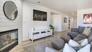 Ein modernes Wohnzimmer mit Kamin, weißem Unterhaltungsschrank, grauem Sofa und einem großen Spiegel.