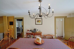 A dining area with a chandelier, a table with a plaid tablecloth, and chairs. There is a coffee maker and a tray with cups on the table. - 4BR Group Getaway on the Chickley River (Hawley)
