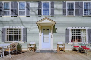 A two-story house with a central entrance, a porch with outdoor furniture, and shutters on the windows. - 4BR Group Getaway on the Chickley River (Hawley)