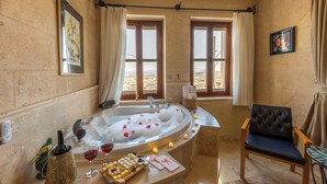 A bathroom with a bathtub, a chair, and a window with curtains. - Peristyle Cave Cappadocia - Special Class (Nevsehir)