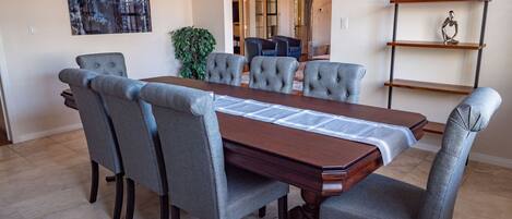 A dining area with a rectangular table, six upholstered chairs, a potted plant, and a globe on a shelf.