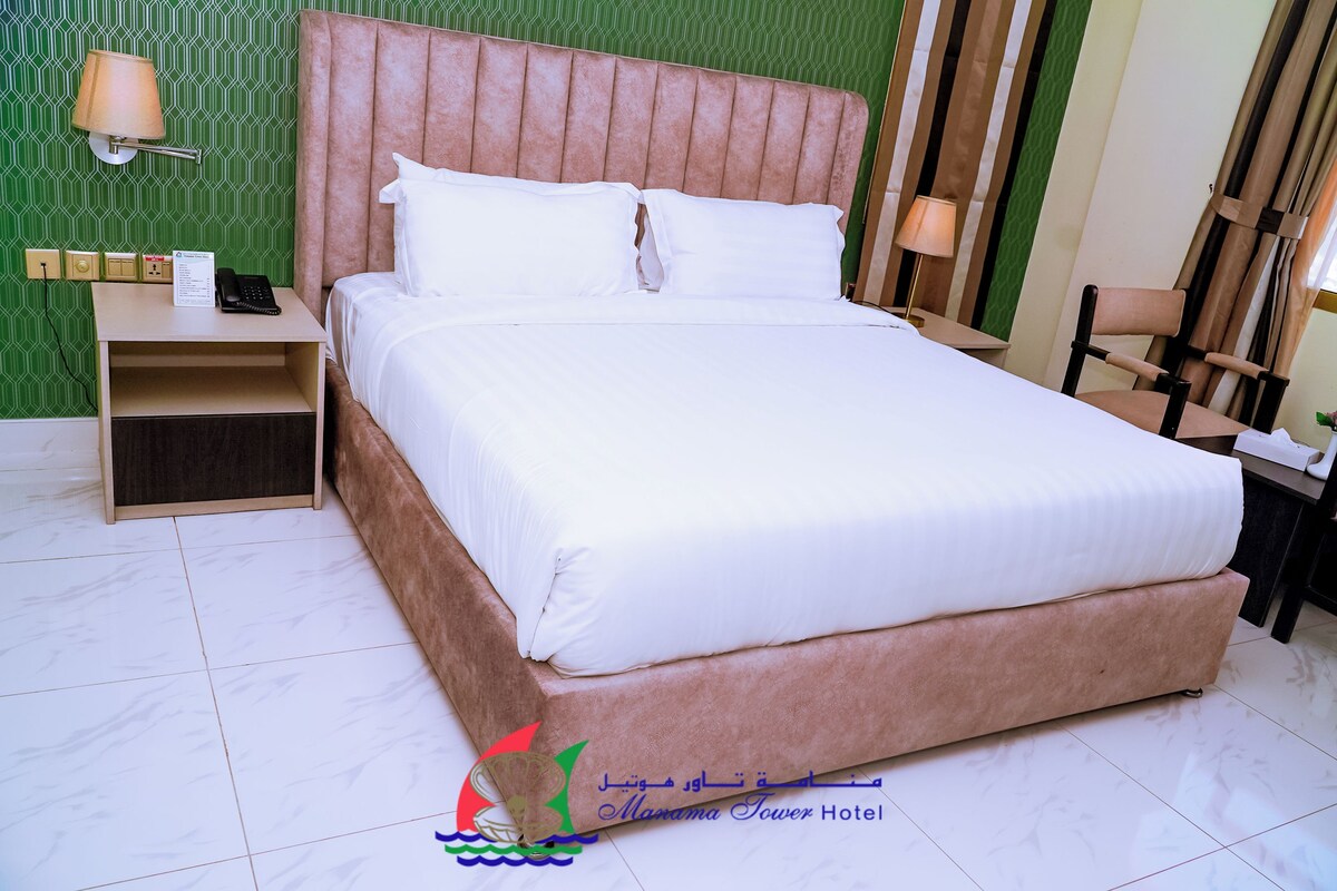 Una habitación de hotel con una cama grande, una mesita de noche con lámpara y una pared verde con estampado.