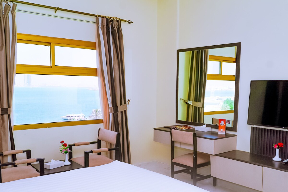 A hotel room with a bed, a desk, a chair, a television, and a window with curtains.
