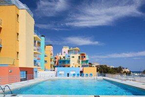 A swimming pool with a view of colorful buildings and a clear sky.
