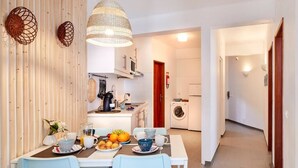 A compact kitchen with modern appliances, a dining area with a table set for breakfast, and a laundry area.