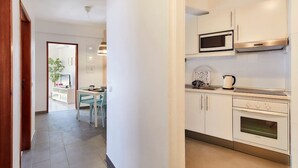 A modern kitchen with white cabinetry, a microwave, a kettle, and an oven.
