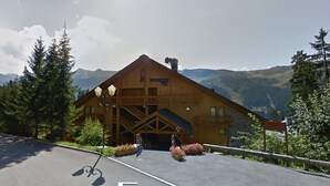 Una cabaña de madera con balcón y vista a la montaña.