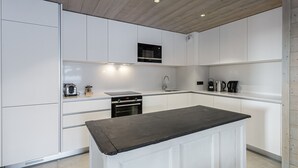 Una cocina moderna con armarios blancos, una isla central y electrodomésticos integrados.