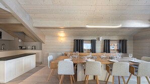 Une cuisine moderne avec une table en bois dressée pour le repas, un four encastré et une grande fenêtre avec des rideaux.