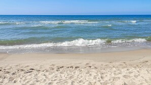 Une plage de sable fin, avec des vagues douces et un ciel bleu clair.