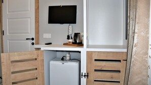 A compact room with a kitchenette, a television mounted on the wall, and a small refrigerator. - Yalı Pansiyon (Kas)