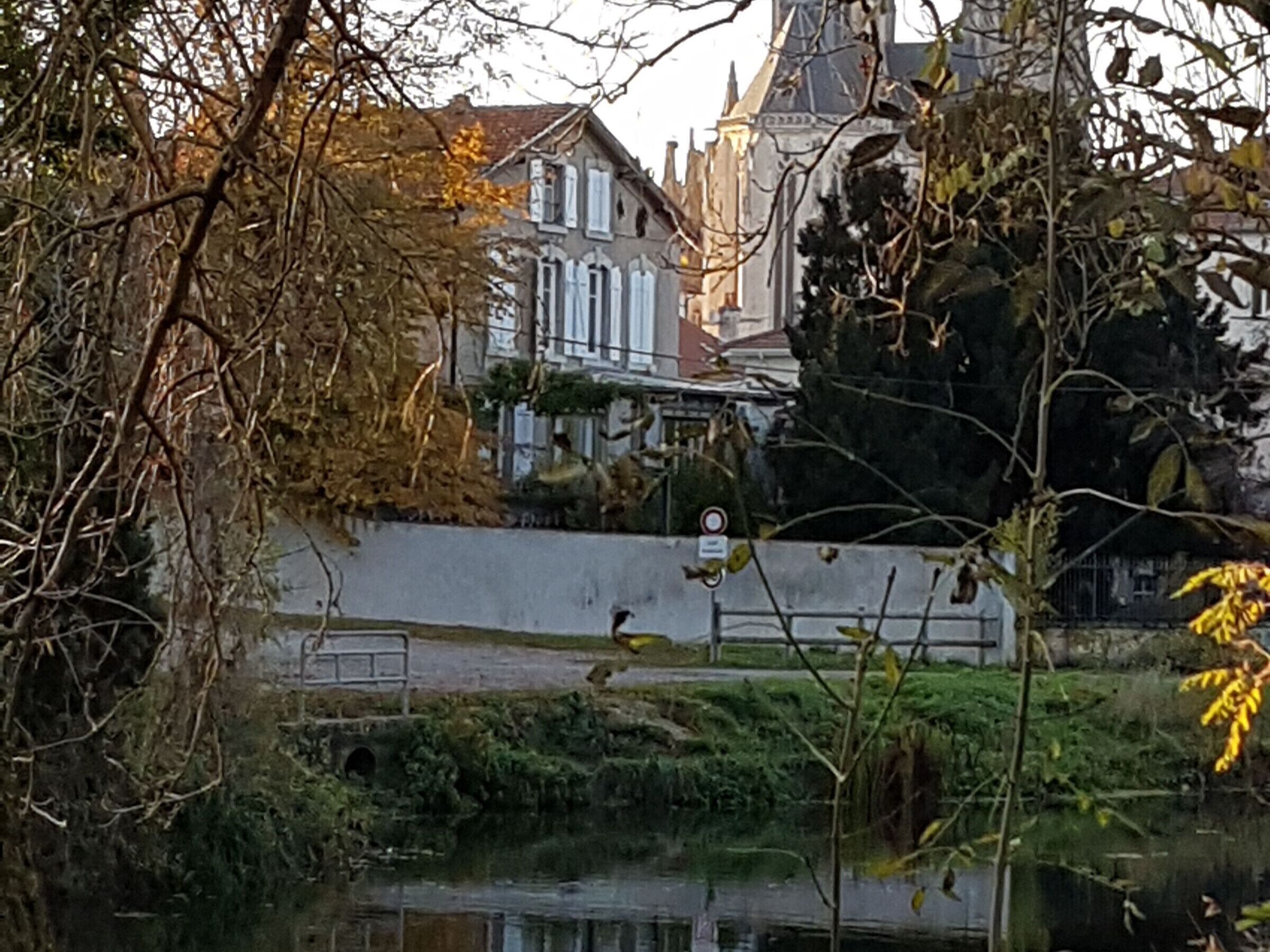 Un bâtiment historique doté d’une architecture traditionnelle, une rivière en premier plan et un panneau indiquant l’interdiction d’accès, bien visible.