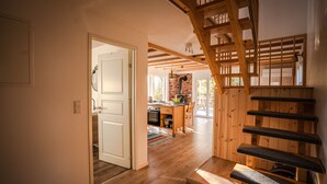 A wooden staircase leading to a lofted area with a kitchen and dining space. - Sunny Swedish cottage surrounded by forest & tranquillity (Åsensbruk)