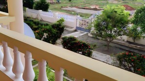 A balcony with a white balustrade overlooking a residential area with greenery and a gated entrance. - 25 minutes to Winneba Beach!!  A quiet family suite with dining and living area. (Winneba)