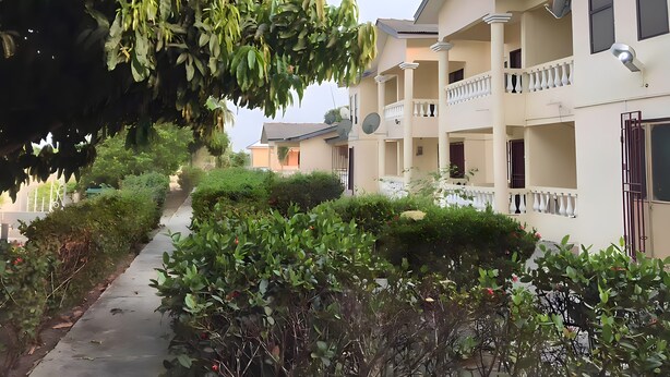 A residential building with multiple balconies, satellite dishes, and a pathway lined with greenery. - 25 minutes to Winneba Beach!!  A quiet family suite with dining and living area. (Winneba)