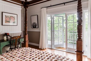 Una habitación con una cama, un escritorio y una silla. Se ve follaje verde a través de la ventana.