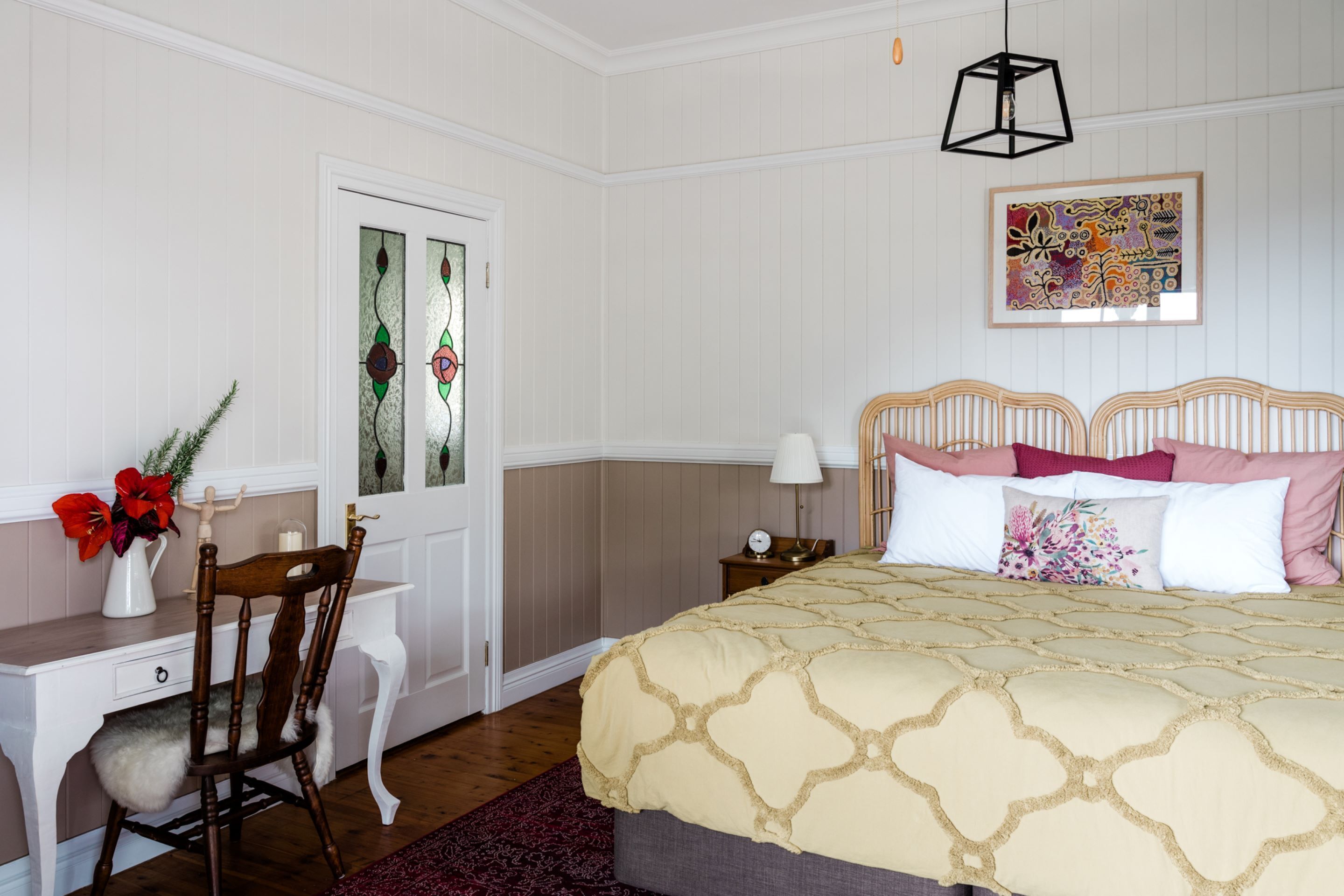 A bedroom with a bed, a desk, a chair, and a door with a window.