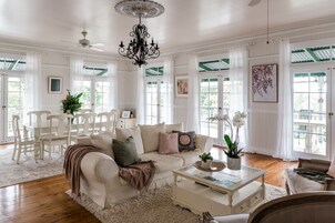 Amplia sala de estar con un sofá blanco, una mesa de centro y un comedor con sillas blancas.