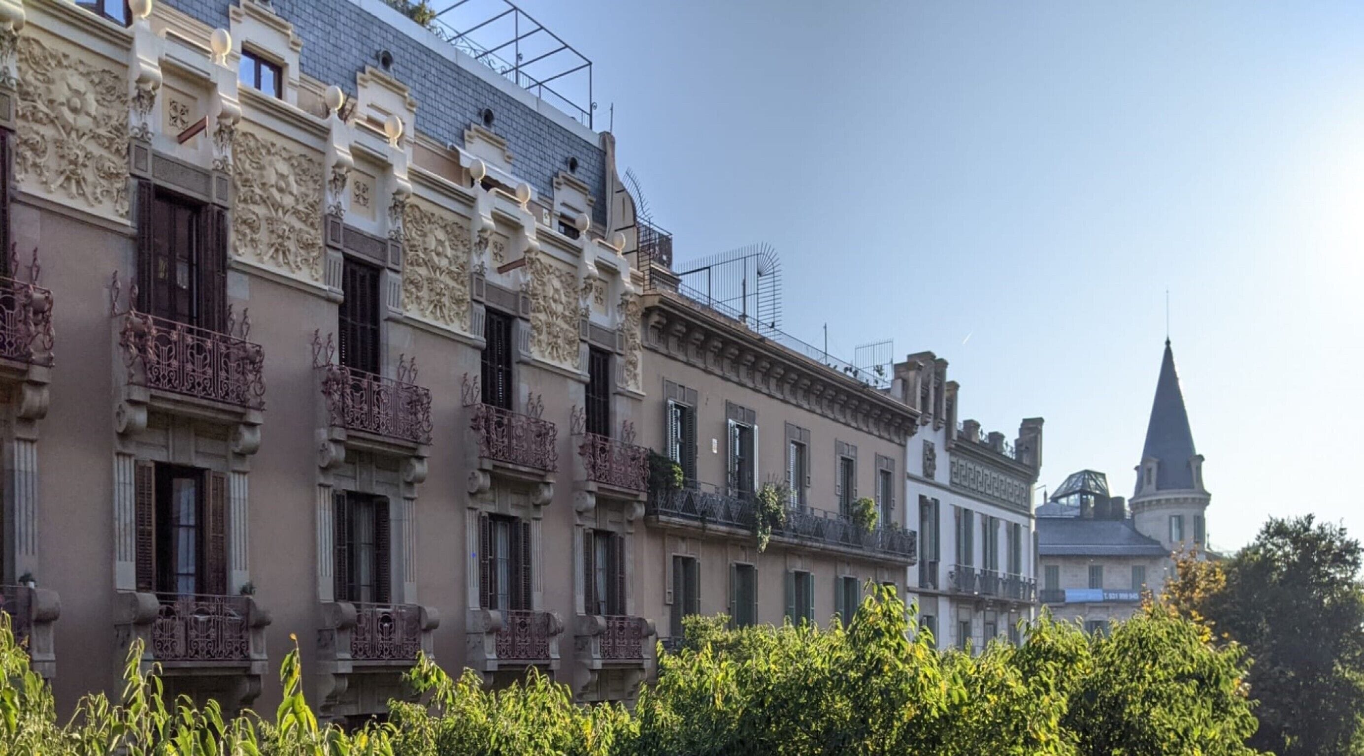 A row of historic buildings with ornate balconies and a church spire in the background.