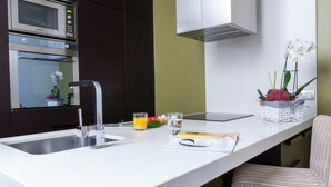 Une cuisine moderne dotée d’un plan de travail blanc, d’appareils électroménagers en acier inoxydable et d’un four à micro-ondes encastré.