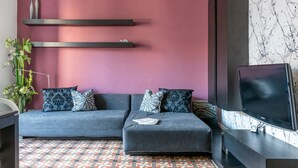 Un salon moderne avec un ensemble de canapés, un téléviseur à écran plat et des coussins décoratifs.