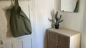 Una puerta blanca con un perchero, un pequeño cactus en maceta, un espejo y un mueble de color claro.