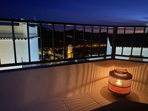 Un balcon offrant une vue sur le paysage urbain au crépuscule, avec un bâtiment imposant doté d’un dôme et d’une tour illuminée.