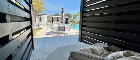 An outdoor patio with a pool, lounge chairs, and a covered seating area.