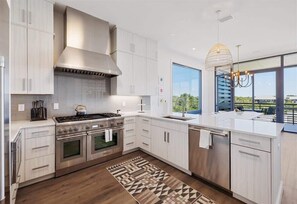 Uma cozinha moderna com armários brancos, fogão de aço inoxidável e uma janela ampla com vista.