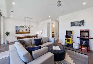 Una sala de estar moderna con sofá, reposapiés y juegos de arcade.