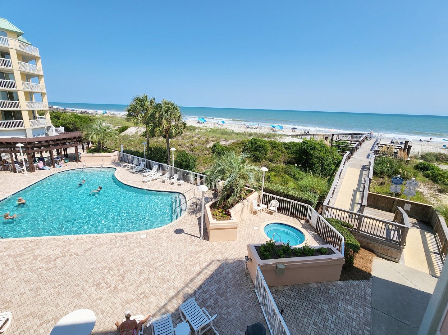 A resort with a swimming pool, lounge chairs, and a beach view.