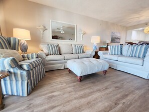 Ein Wohnzimmer mit einem Ecksofa, einem gestreiften Sessel und einem passenden Hocker.